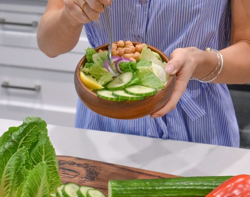 person holding green vegetable on brown ceramic plate